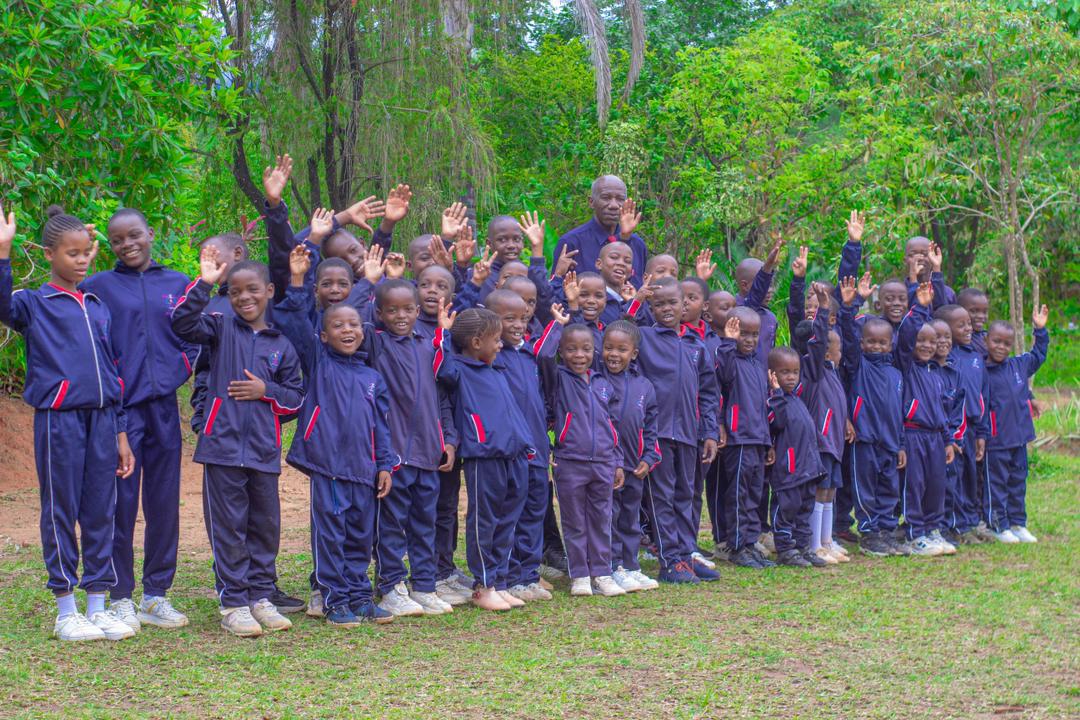 Bethel College learners smiling and waving together outdoors in 2025