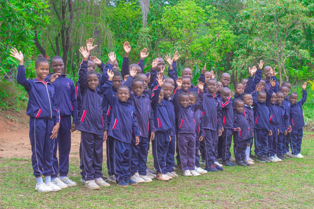 Learners waving towards the camera in the school grounds